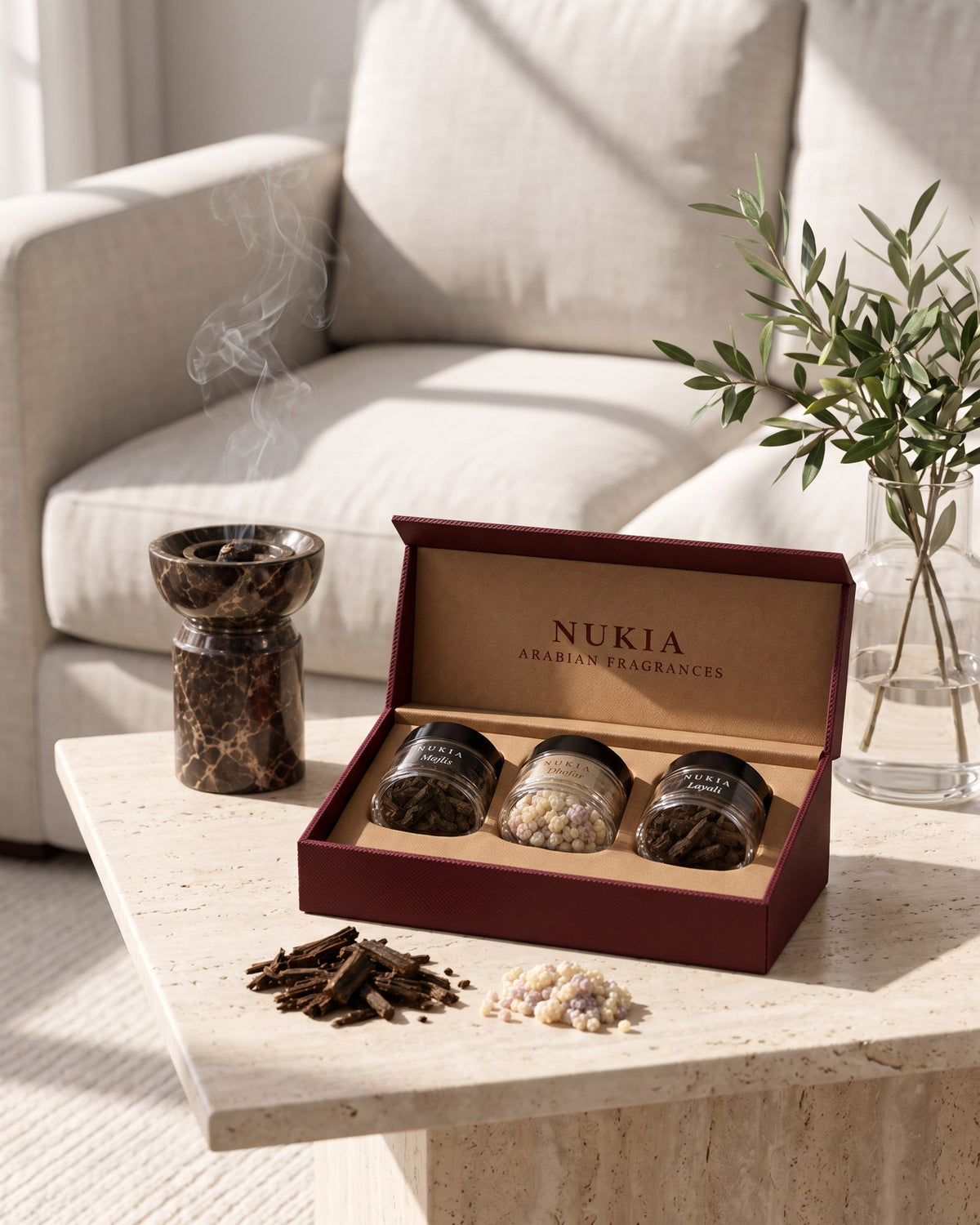 The trio open on a sunlit side table next to a marble burner with soft smoke