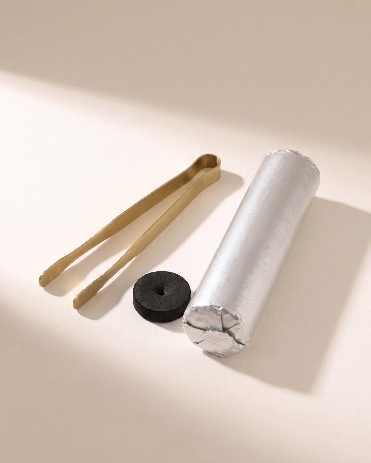Brass tongs and charcoal discs, included in the set